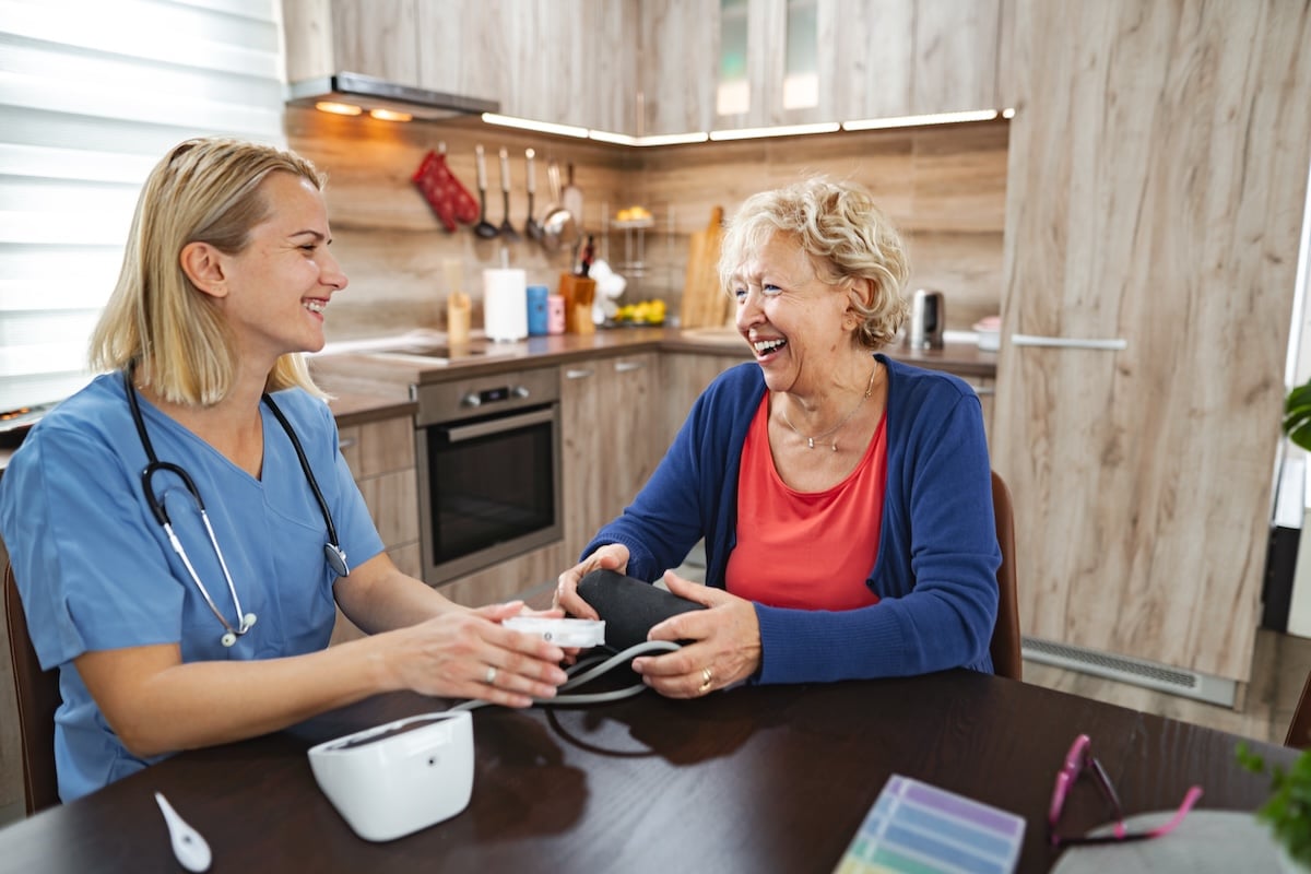 An in-home care provider works with a client in her home, taking her blood pressure.
