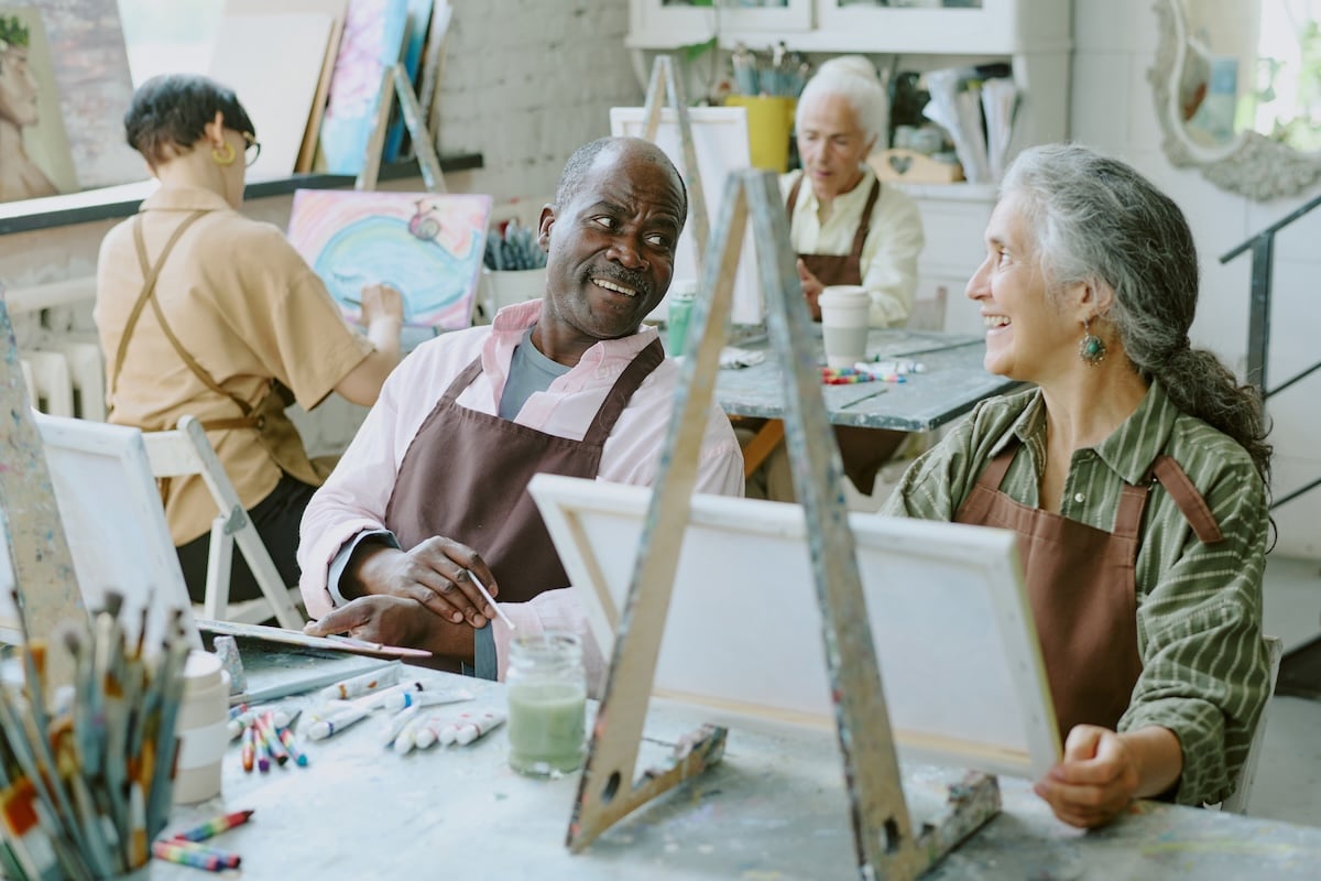 Older adults paint in an art studio. Having opportunities to enjoy hobbies together is one advantage of a retirement living community. 